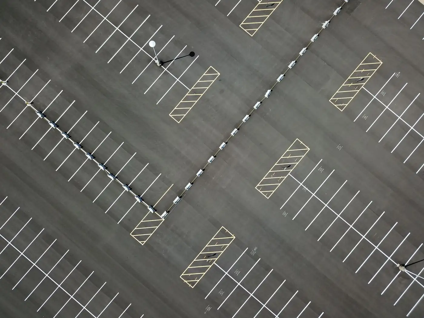 Aerial view of an empty parking lot with angled stalls and hatched markings