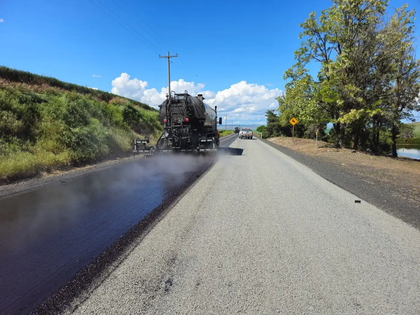 Asphalt paver laying a fresh mat on a two-lane road