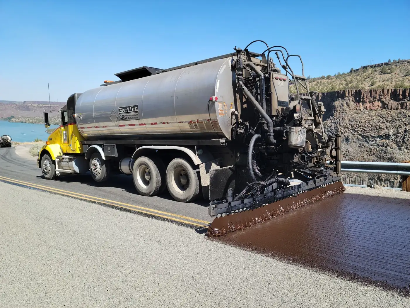 Chip seal distributor truck spraying binder across a road