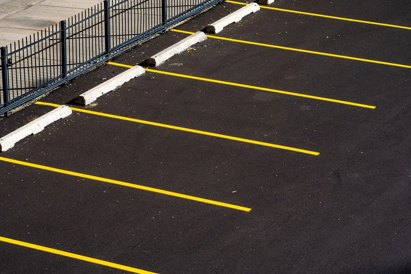 Freshly sealed black parking lot with bright yellow stall stripes