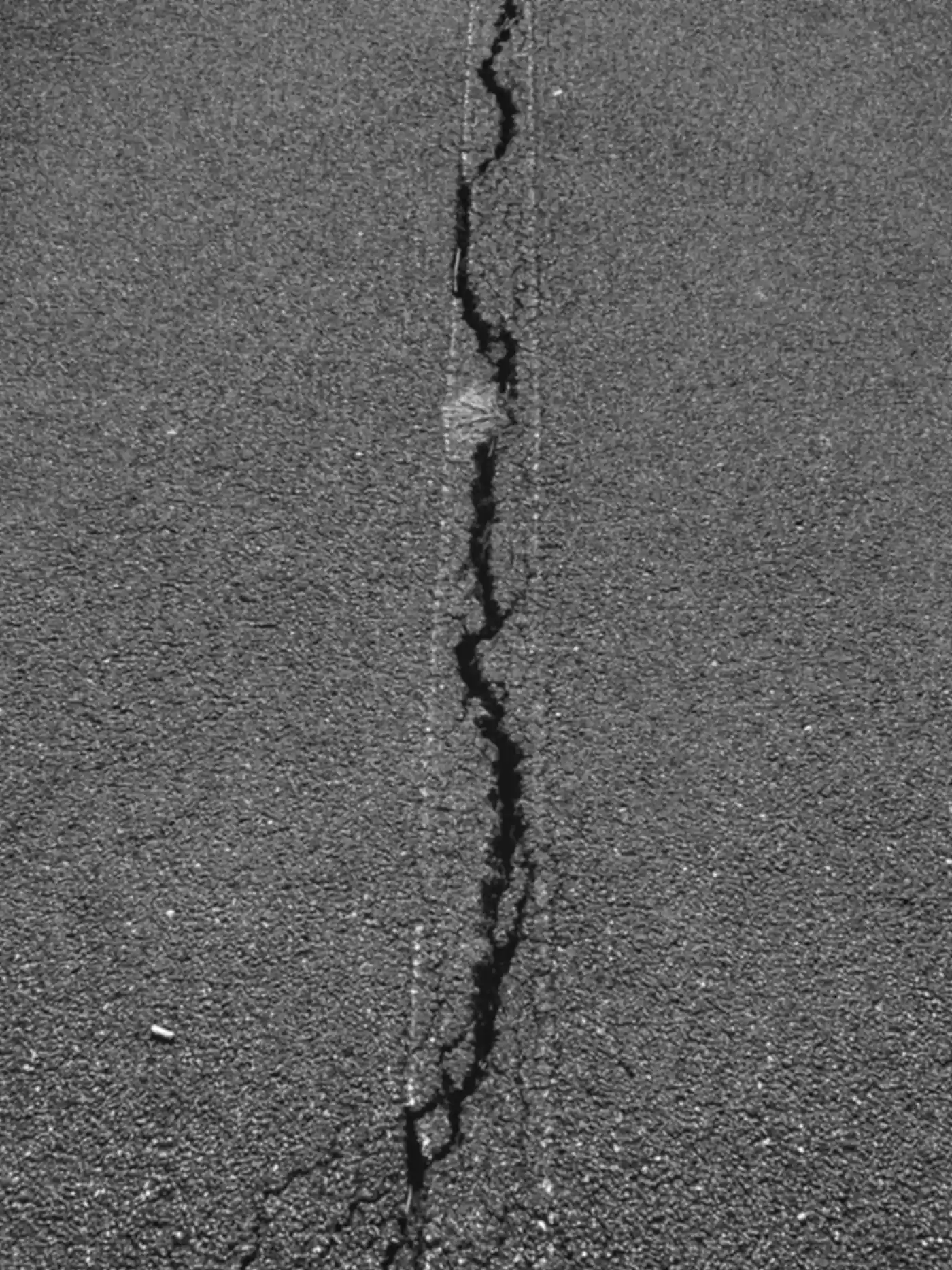 Long open crack splitting an asphalt surface