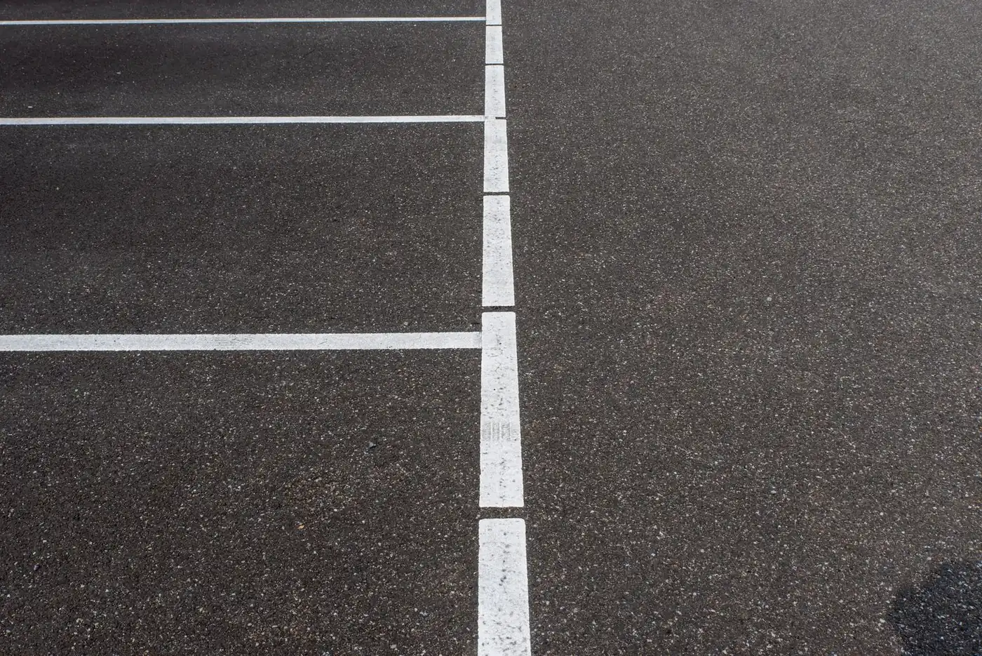 Dark asphalt parking lot with crisp white stall lines