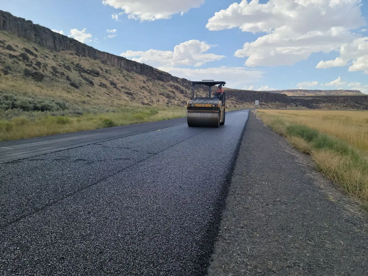 Steel drum roller compacting a newly paved asphalt road