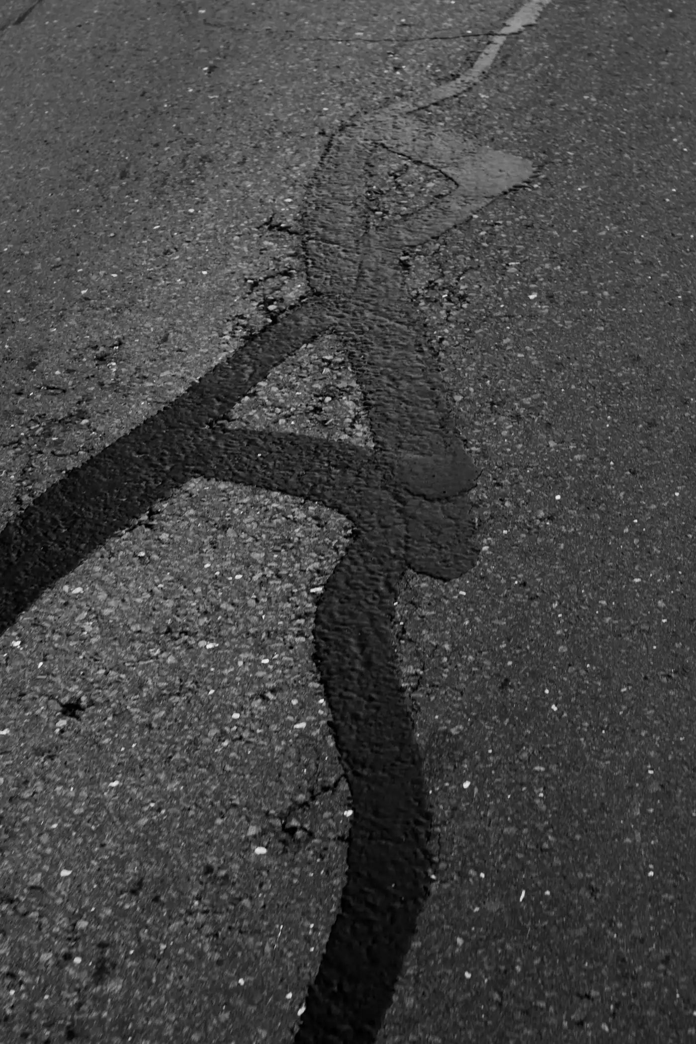 Asphalt surface with long black bands of crack sealant
